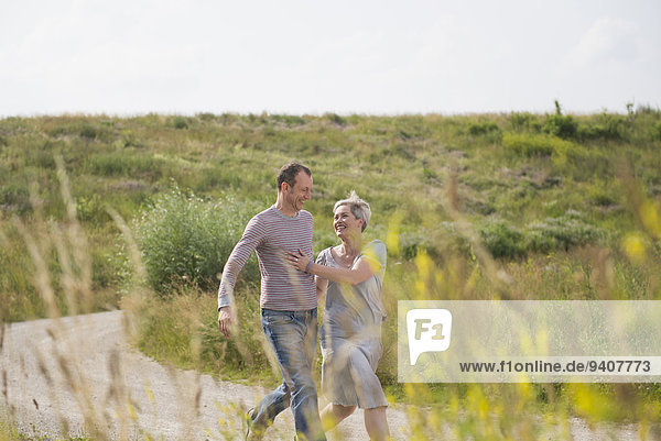 Mature couple running on field in summer  smiling