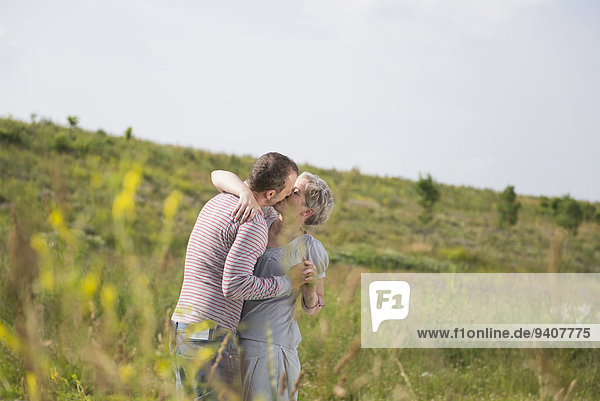 Mature couple kissing in field