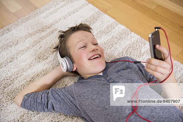 Boy at home listening to music from smartphone