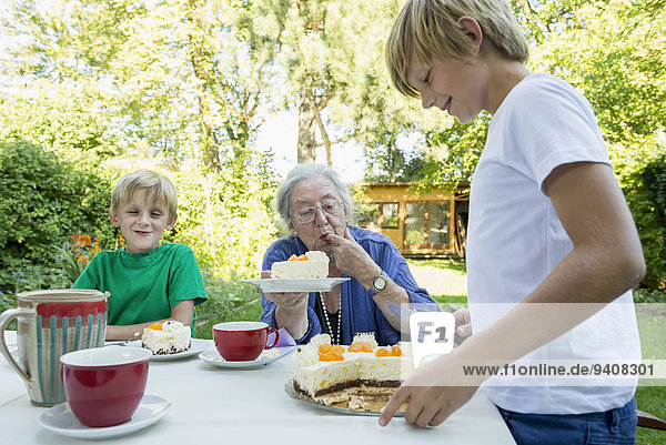 Grandmother and her two grandsons with cream cake