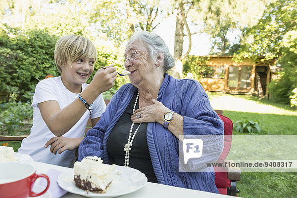 Großmutter Enkelsohn Kuchen Sahne füttern