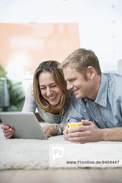 Couple lying on floor with digital tablet