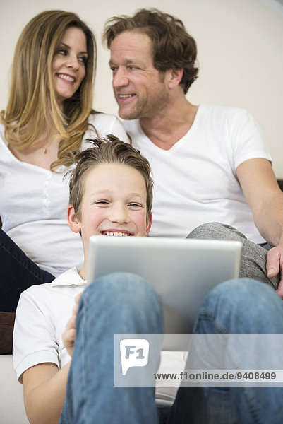 Happy family in living room with digital tablet