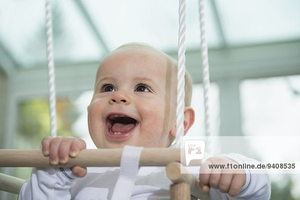 Portrait of laughing toddler sitting in a swing