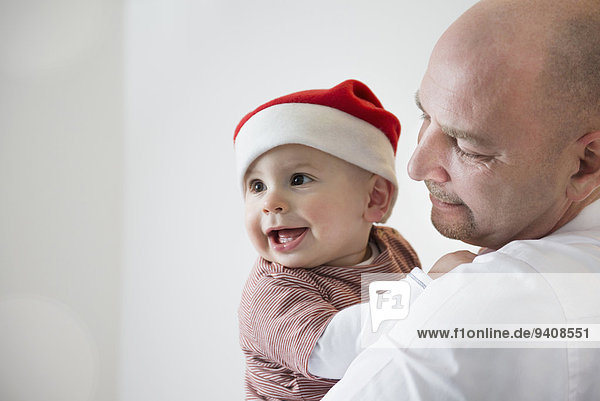 Toddler with Christmas cap in the arms of his father