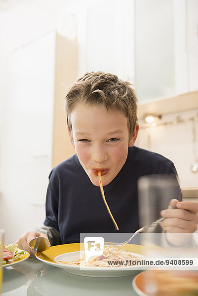 Boy eating spaghetti in kitchen