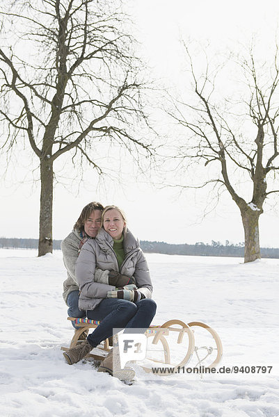 Couple sitting on sledge  smiling