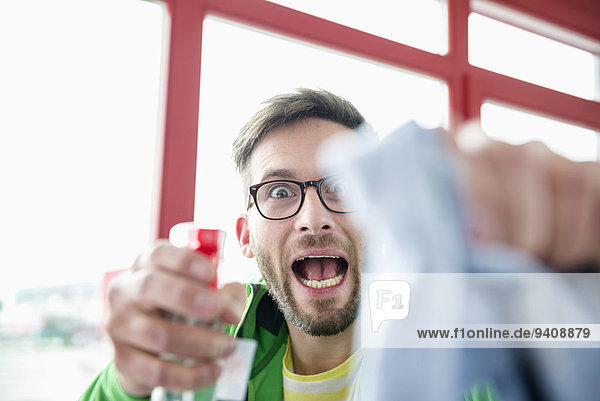 Young man holding cleaning liquid bottle and cloth