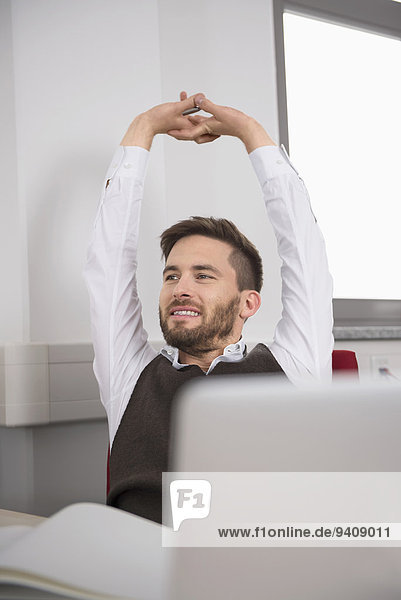Young man relaxing office outstretched arms