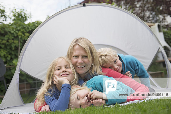 Mother with young kids small tent garden lawn