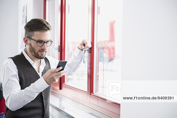 benutzen Mann Fenster Büro jung Smartphone