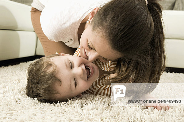 Mother and son are romping in living room  smiling
