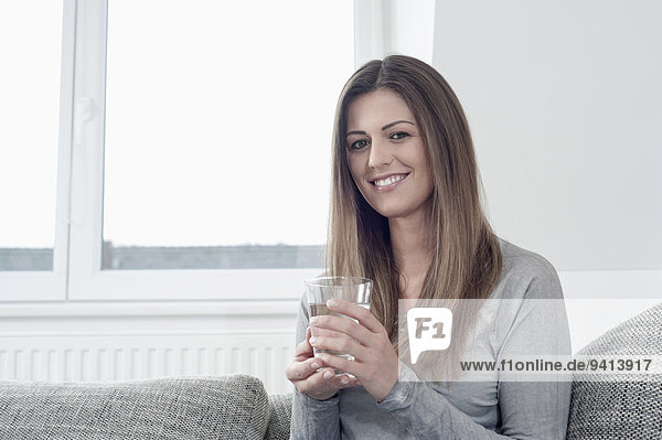 Portrait of smiling young woman holding glass of water