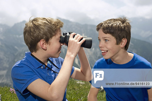 Two teenage boys holding binoculars in Alps