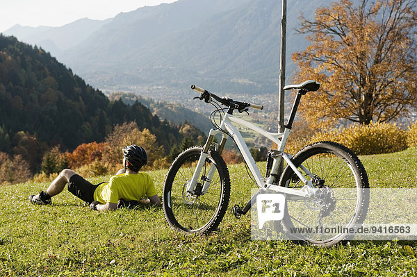 Mountainbiker resting on grass enjoying view