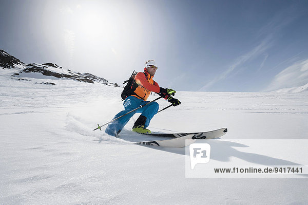 Man skiing downhill powder snow Alps sunshine