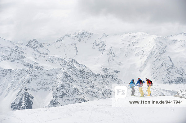 Alps winter mountains three skiers snow
