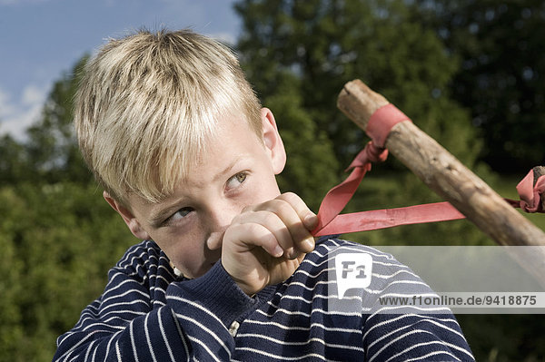 Portrait boy holding handmade wooden slingshot