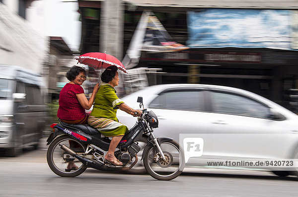 Zwei Frauen auf einem Motorrad  mit rotem Sonnenschirm  Chiang Mai  Nordthailand  Thailand