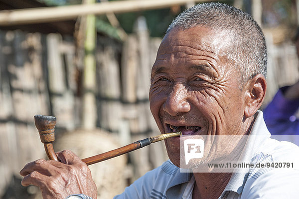 Elderly man from the Akha people  hill tribe  ethnic minority  smoking a pipe  portrait  Chiang Rai Province  Northern Thailand  Thailand