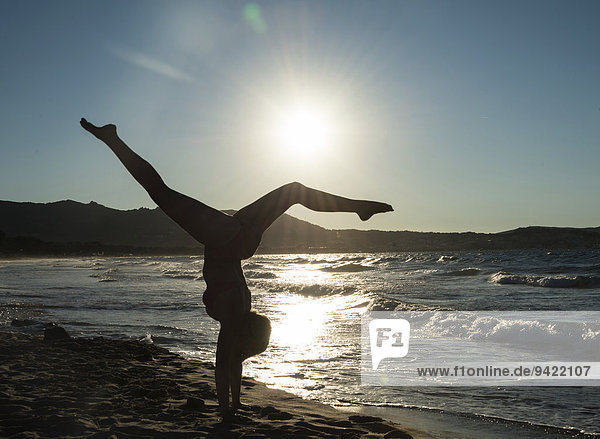 Junge Frau turnt am Strand  Gegenlicht  Korsika  Frankreich