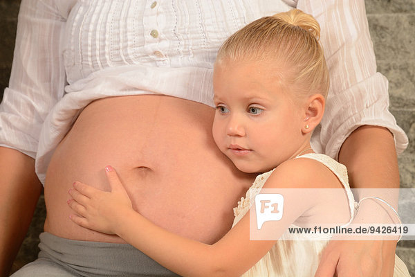 Mädchen  3 Jahre  mit seinem Kopf am Bauch der schwangeren Mutter  Schweden