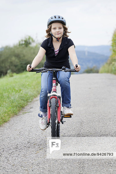 Girl  8 years  riding a bicycle wearing a helmet