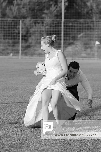 Trash the dress  Braut und Bräutigam spielen Rugby  Bräutigam bringt Braut zu Fall