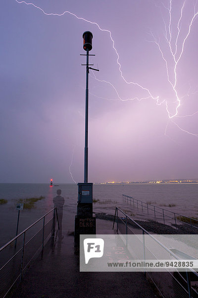 Gewitter mit Blitz und Wetterwarnleuchter  stehender Mensch beobachtet das Gewitter  Bodensee  Konstanz  Baden-Württemberg  Deutschland  Europa