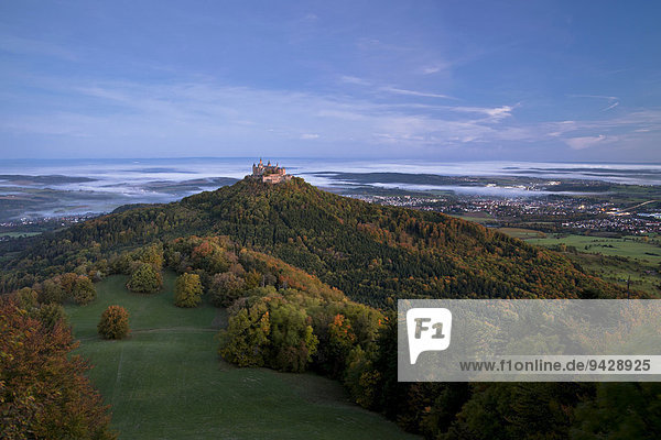 Burg Hohenzollern Castle in the morning light with autumn forests  early morning fog  Swabian Alb  Baden-Wuerttemberg  Germany  Europe