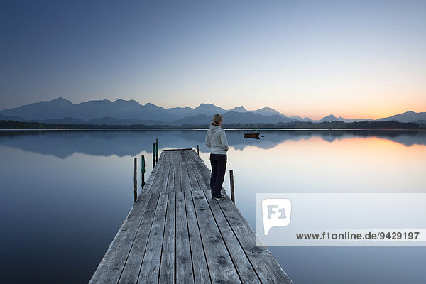 Woman on jetty at Lake Hopfensee in the evening  Allgaeu  Bavaria  Germany  Europe