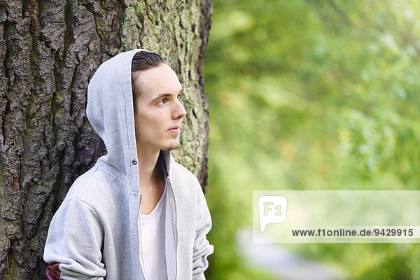 Junger Mann steht alleine in einem Wald  nachdenklich
