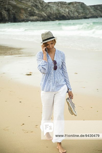 Reife Frau beim Plaudern auf dem Smartphone,  Camaret-sur-mer,  Bretagne,  Frankreich