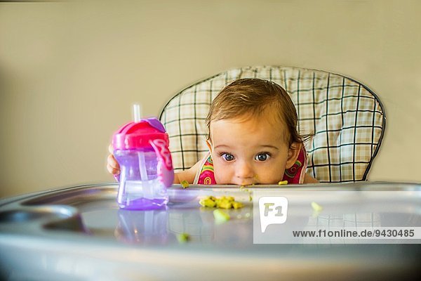 Portrait of shy baby girl in high chair
