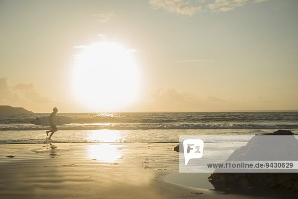 Erwachsener Mann  der zum Meer rennt  Surfbrett hält