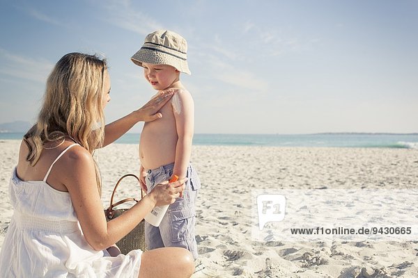 Mid adult mother applying sun lotion to young son on beach  Cape Town  Western Cape  South Africa