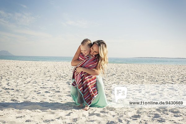Mittlere erwachsene Mutter wickelt Sohn in ein Handtuch am Strand  Kapstadt  Westkap  Südafrika