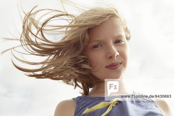 Portrait eines Mädchens mit fliegendem Haar an der luftigen Küste