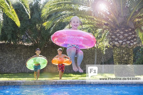 Mädchenspringen mit aufblasbarem Ring im Gartenschwimmbad