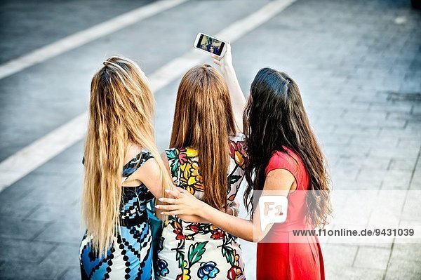 Rückansicht von drei jungen Frauen  die Selfie mit Smartphone nehmen  Cagliari  Sardinien  Italien