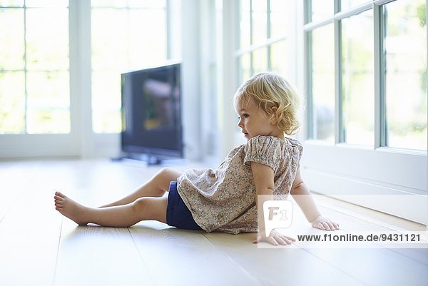 Portrait weibliches Kleinkind auf dem Wohnzimmerboden sitzend