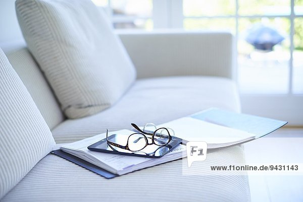Brille und Tagebuch auf dem Wohnzimmersofa