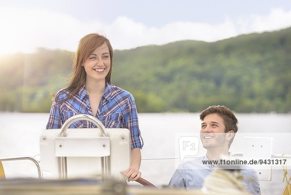 Junge Frau steuert Yacht über See unter hellem Sonnenlicht
