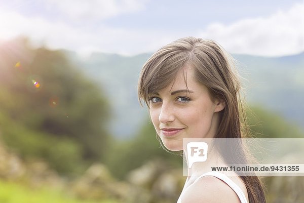 Porträt einer jungen Frau  die in sonniger Landschaft lächelt  Nahaufnahme