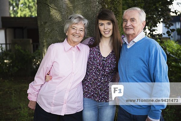 Großeltern und Enkelin am Baum stehend