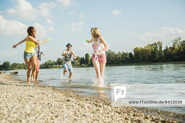 Friends playing with water pistols in lake