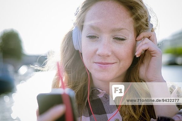 Nahaufnahme einer jungen Frau  die Musik über Kopfhörer auf der Straße hört.