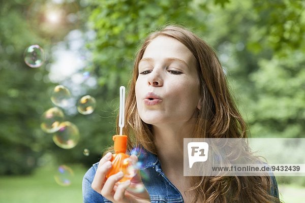 Junge Frau bläst Blasen im Garten
