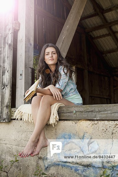Young woman sitting by barn  portrait