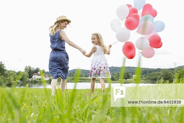 Mutter und Tochter im Feld mit Luftballons